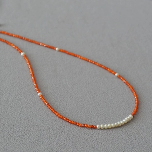 Detail of orange faceted gemstone beads with white freshwater pearls on a necklace