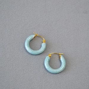 Detail of light blue marble textured hoop earrings with gold-plated metal hooks