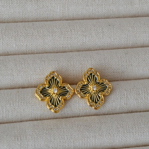 Macro shot of gold clover earrings with blue enamel and sparkling crystal accents