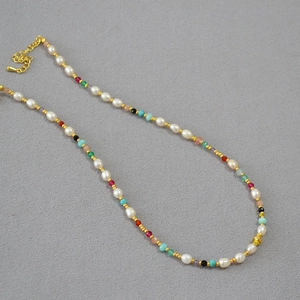 Détail de perles colorées et perles d'eau douce avec fermoir doré sur tissu gris