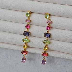 Close-up of colorful geometric glass gemstones in a gold drop earring setting
