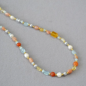 Dettaglio ravvicinato della collana con perle barocche, gemme colorate e distanziatori dorati