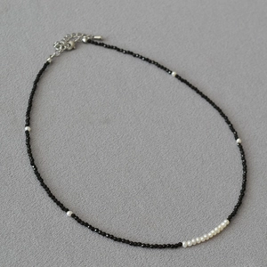 Detail of beaded necklace with black faceted stones, white pearls, and silver lobster clasp