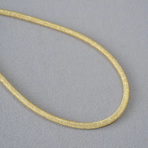 Detailed macro view of delicate gold woven mesh necklace showing fine metallic craftsmanship