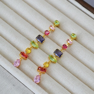 Colorful geometric crystal drop earrings with gold-plated finish on white velvet display