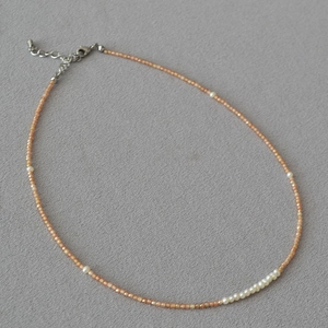 Macro shot of orange-pink faceted beads with white pearls and silver lobster clasp detail
