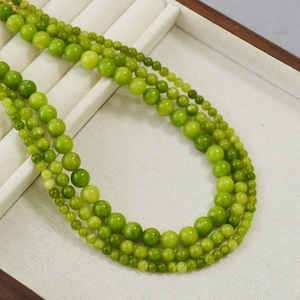 Collier rétro en perles de pierre vert olive sur plateau blanc pour un style d'été