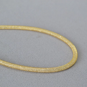 Detail of gold-plated woven mesh chain showing fine texture and sparkling finish