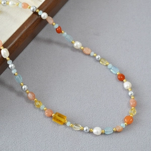 Dettaglio ravvicinato di collana con perle barocche e pietre preziose multicolore