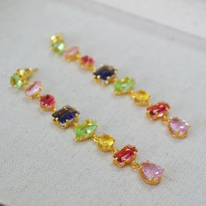Macro shot of colorful geometric glass earrings with multi-shaped stones in gold frames