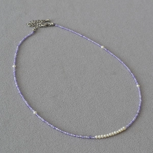 Close-up of purple faceted beads with white freshwater pearls on a delicate necklace