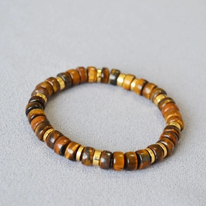 Tiger eye stone bead bracelet with golden spacers on light gray textured background