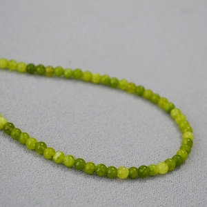 Détail macro de perles rondes en pierre naturelle vert olive avec une texture lisse
