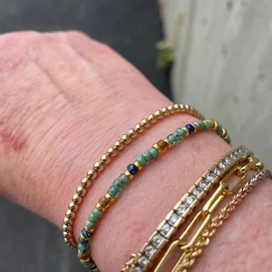 Detail showing stacked bohemian bracelets with turquoise beads and gold chains on wrist