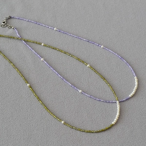Detailed view of beaded necklaces with freshwater pearls in light purple and olive green