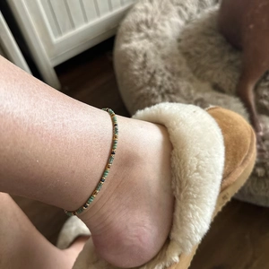 Detail of bohemian handmade beaded anklet with green, gold and blue antique beads