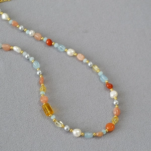 Collana di perle barocche con acquamarina blu e perle di citrino su tessuto grigio