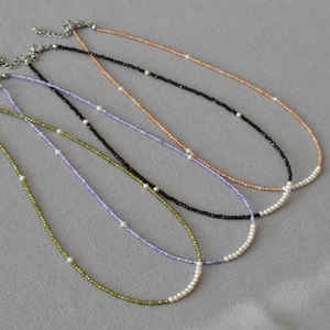 Detailed macro view of delicate beaded necklaces with colorful zircon and freshwater pearls