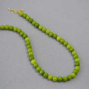 Détail macro du collier de perles en pierres vertes avec extension dorée ajustable