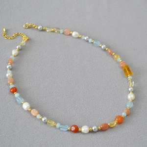 Dettaglio della collana di perle barocche con acquamarina e citrina su sfondo grigio