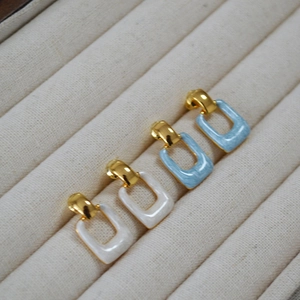 Detail of square geometric earrings with blue and white enamel and gold-plated hooks