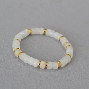 Detail of grey agate beads bracelet with gold spacers on textured grey background