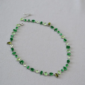 Detail of silver necklace featuring mixed-cut green gemstones with lobster clasp