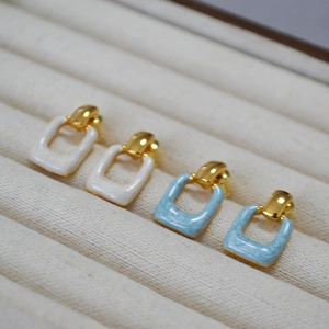 Minimalist square enamel earrings in cream and blue with gold plating on velvet display