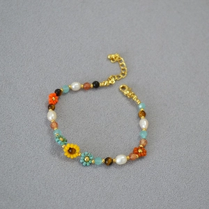 Detail of bohemian handmade beaded bracelet with colorful flowers and adjustable gold clasp