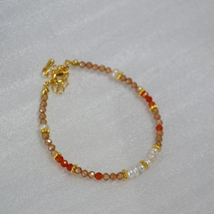 Détail de bracelet avec perles de zircon champagne et perles d'eau douce sur chaîne dorée