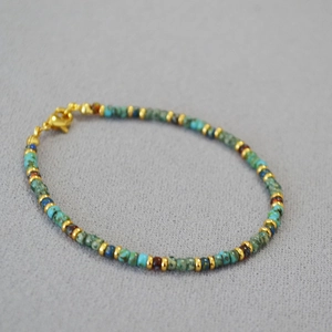 Detailed shot of handmade bohemian beaded bracelet with turquoise stones and gold clasp
