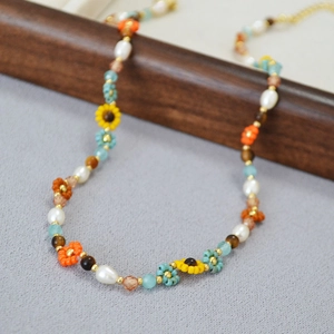Détail d'un collier bohème avec perles de fleurs faites à la main et fermoir doré