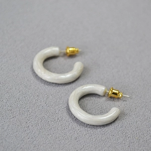 Detail of C-shaped marble resin hoop earrings with gold plated 925 silver pins