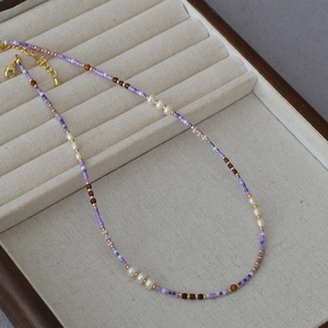 Detailed macro view of purple seed beads and white pearls on an elegant summer necklace