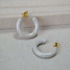 Detail of C-shaped hoop earrings with grey marble resin and golden metal studs