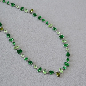 Detailed view of silver necklace with multi-shaped green gemstones in gradient shades