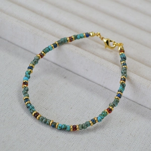 Detailed close-up of Bohemian Miyuki beaded bracelet with golden lobster clasp on fabric