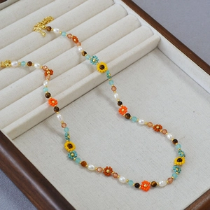 Détail d'un collier bohème avec perles, fleurs de tournesol et fermoir mousqueton doré