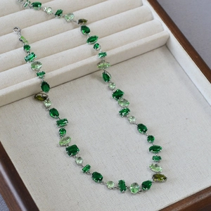 Detail of silver necklace featuring multi-shaped green gemstones in a mosaic pattern
