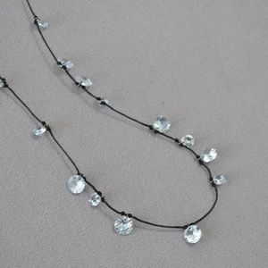 Elegante collana in cordino nero con fiori di zircone scintillanti su sfondo grigio