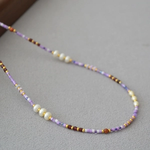 Macro detail of violet beads and white pearls on a summer handmade beaded necklace