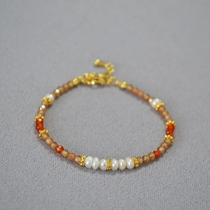 Détail du bracelet en perles d'eau douce avec pierres précieuses orange et perles dorées