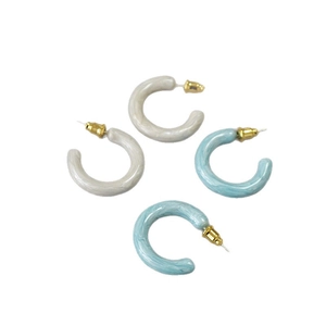 Minimalist C-shaped marble enamel hoop earrings in blue and white on a white background