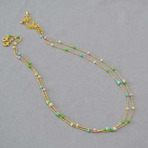 Detail of a gold double-layer chain necklace with colorful small rectangular beads