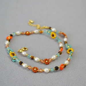 Détail du collier de perles avec breloques tournesol et fermoir mousqueton doré