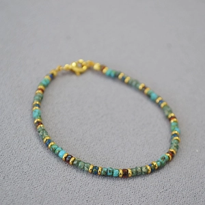 Close-up of Bohemian beaded bracelet with turquoise and gold spacers on dark background