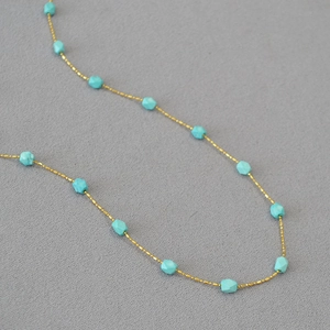 Minimalist gold beaded chain necklace with geometric blue turquoise stones in a retro style