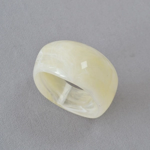 Détail macro de la bague large en acrylique crème avec texture élégante de marbre blanc