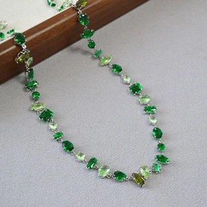 Macro detail of multi-shaped green gemstone necklace with various cuts and silver base