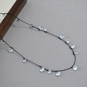 Dettaglio della collana in cordino nero con pendenti a fiore in zircone scintillante